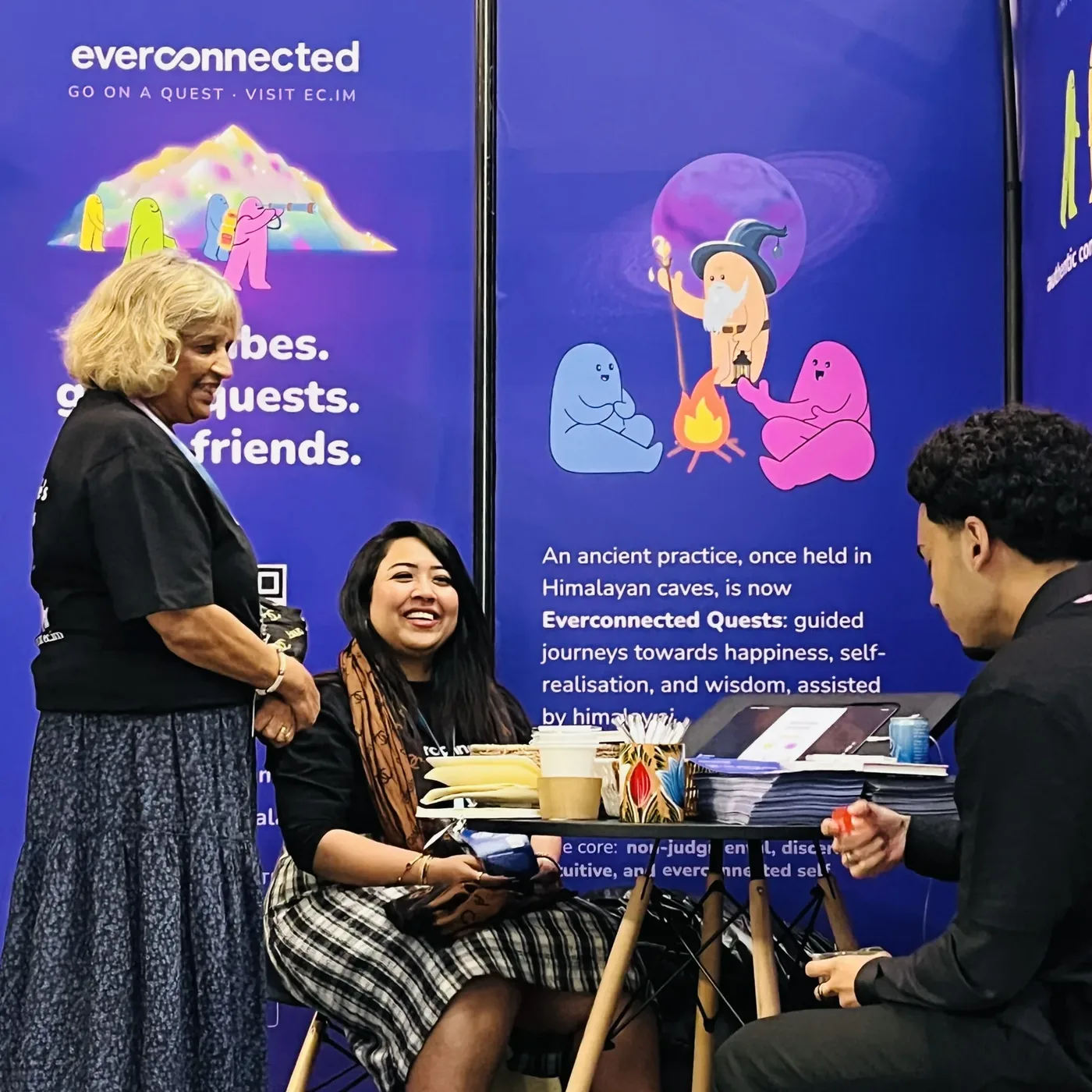 At the table in front of the Everconnected Quests wall